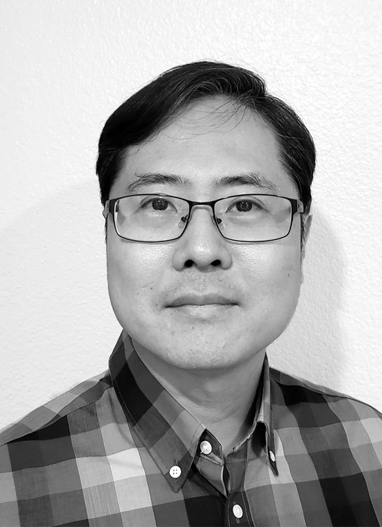 This is a grayscale portrait of Dr. Lee, he is wearing a checkered shirt against a light background.