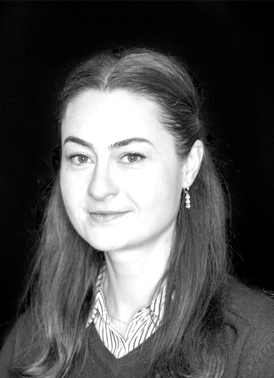 This is a grayscale portrait of Dr. Maftei. She is smiling towards the camera against a black background.