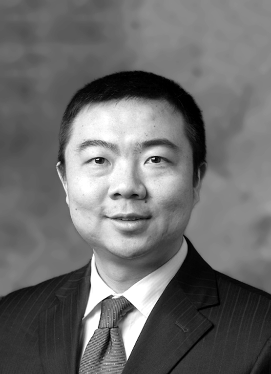 This is a grayscale portrait of Dr. Zhang. He is looking towards the camera wearing a pinstripe suit and a tie.
