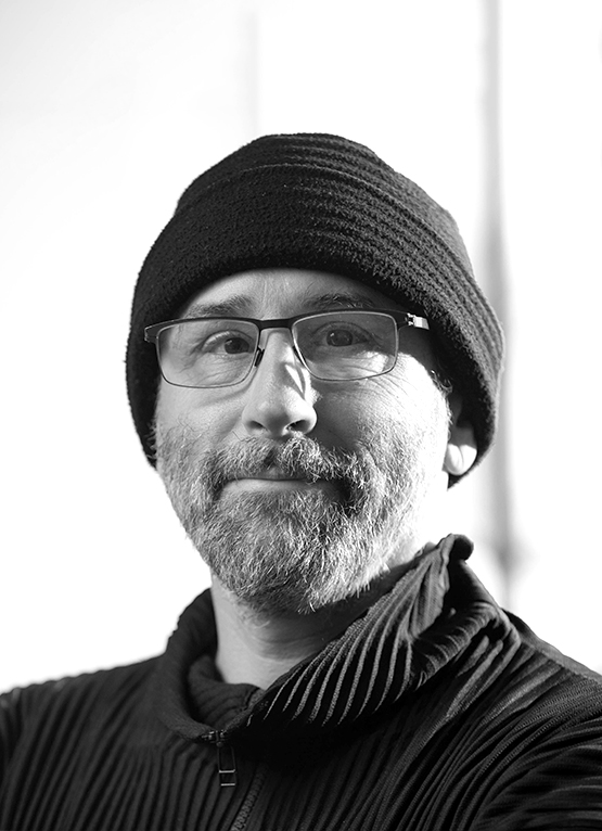 This is a grayscale portrait of Dr. Gerber, he is smiling towards the camera, wearing a beanie.