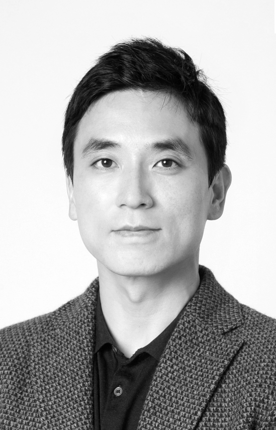 This is a soft-light portrait of Dr. Koo in grayscale. He is wearing a woven jacket and a dark shirt. Against a white background.